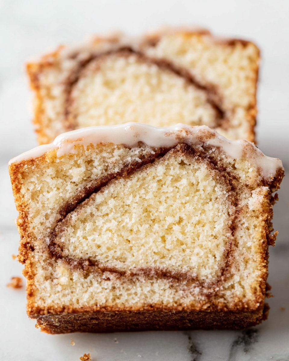 The image shows two thick slices of cinnamon swirl cake, stacked slightly overlapping on a white marbled surface. Each slice has two main layers: a light golden brown crust on the top and bottom edges with a soft, pale yellow crumb in the middle. A thin, darker brown cinnamon swirl runs through the inner layer, creating a curved line pattern. The top slice has a light glaze coating with a smooth texture, while the bottom slice's glaze is partially visible and appears slightly shiny. The overall texture of the cake looks soft and fluffy. photo taken with an iphone --ar 4:5 --v 7