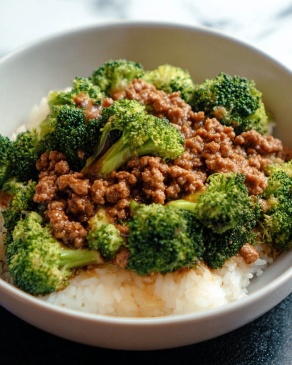 A white bowl filled with a layer of plain white rice at the bottom, topped with cooked broccoli florets that are bright green with a soft texture, and covered with a layer of cooked ground meat in a thick brown sauce. The broccoli and meat are mixed but mostly kept separate in clusters on top of the rice. The background is a white marbled surface. Photo taken with an iphone --ar 4:5 --v 7