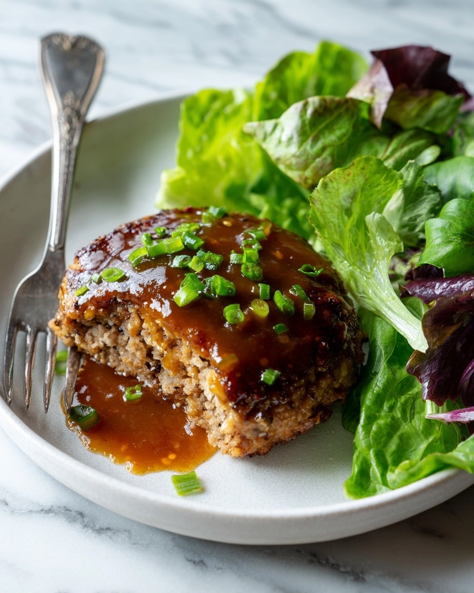 The dish shows a white plate with a piece of cooked patty covered in shiny brown sauce, topped with small chopped green onions. The patty has a rough texture and is placed on the left side of the plate. On the right side of the plate, there are fresh green lettuce leaves, some with purple edges, arranged loosely. A silver fork with some patty on its tines is resting on the plate's left edge. The background has a white marbled texture. photo taken with an iphone --ar 4:5 --v 7