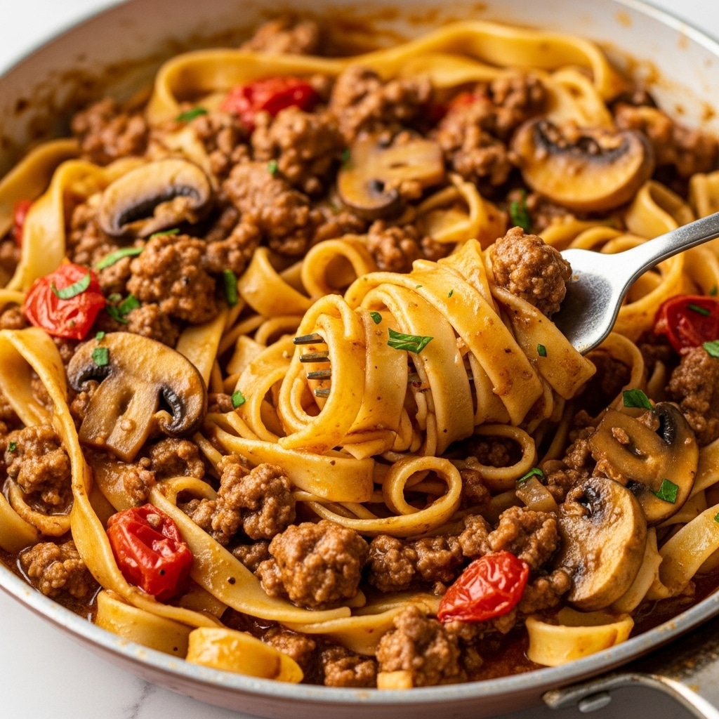 A close-up view of a pan filled with wide, flat tagliatelle pasta coated in a rich, brown meat sauce with visible chunks of cooked ground meat and small pieces of red tomato. The sauce has a glossy texture that clings to the pasta strands, and sliced mushrooms are mixed in throughout. A fork is twirling a portion of the pasta, revealing the layers of pasta wrapped around the fork and the sauce's thick texture. Small bits of green herbs sprinkle the dish, adding a touch of color. The pan has a slightly worn, rustic look, sitting against a white marbled background. Photo taken with an iphone --ar 4:5 --v 7